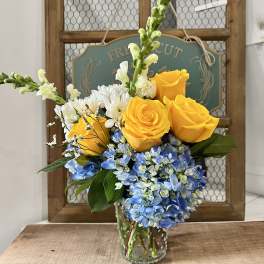 Yellow roses and blue hydrangeas in a glass vase