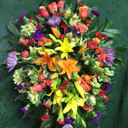 Colorful standing spray with lilies, roses, and purple blooms