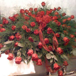 Large arrangement of red roses with greenery in a casket