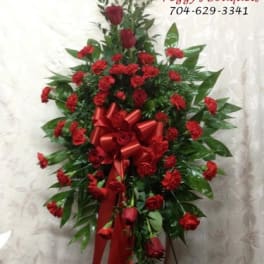 Tall red rose and carnation standing spray with a red ribbon