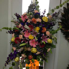 Large standing floral spray with mixed bright flowers on a metal easel