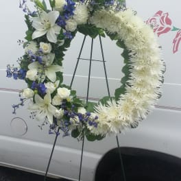 White floral wreath on a standing easel with blue accents