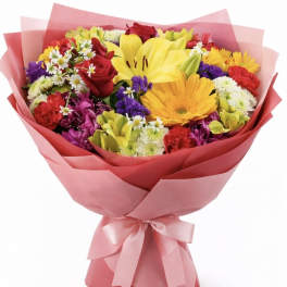 Colorful mixed bouquet with roses, lilies, and daisies wrapped in pink paper
