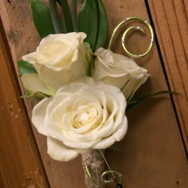 White rose boutonniere with green leaves and curled wire accents