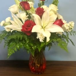 Red roses and white lilies in a red glass vase