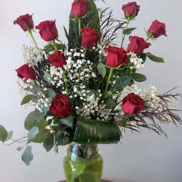 Tall bouquet of red roses with white baby's breath in a glass vase