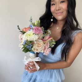 Woman holding a pastel bouquet with roses, calla lily, and white ribbon