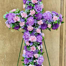 Standing floral cross of lavender and pink blooms on a wire easel