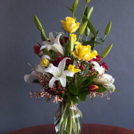 Mixed bouquet of yellow roses and white lilies in a glass vase