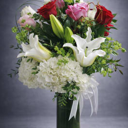 Bouquet of red and pink roses with white lilies in a glass vase