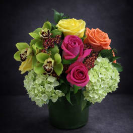 Colorful bouquet of roses, orchids, and hydrangeas in a dark vase