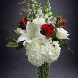 Red and white roses with lilies and hydrangeas in a glass vase