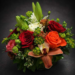 Mixed bouquet with red, orange, and white roses in a low vase