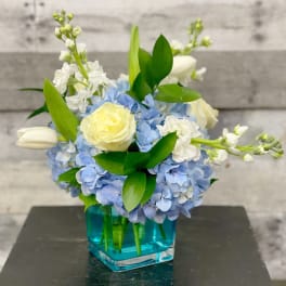 Blue hydrangea bouquet with white roses in a blue glass vase