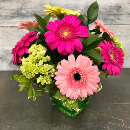 Bouquet of pink, peach, and yellow gerbera daisies in a green vase