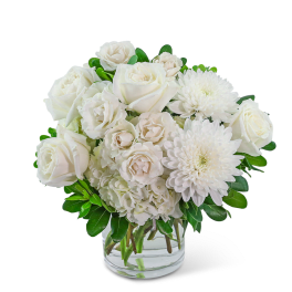 White roses and chrysanthemums arranged in a clear glass vase