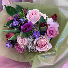Bouquet of pink and purple roses with small purple flowers wrapped in paper