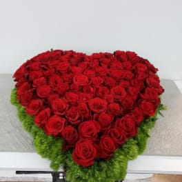Heart-shaped arrangement of red roses with a green border