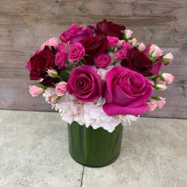 Pink and burgundy roses arranged in a green glass vase