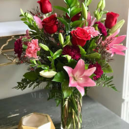 Bouquet of red roses, pink lilies, and carnations in a glass vase