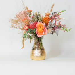 Mixed bouquet in a gold vase with orange and pink blooms
