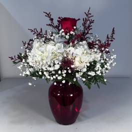 White flowers and a red rose in a burgundy vase