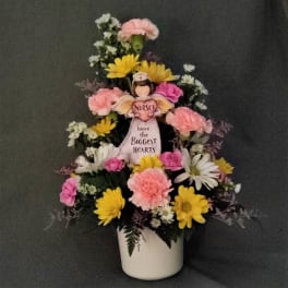 Flower arrangement with a nurse figurine in a white pot