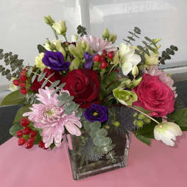Mixed bouquet of roses, lisianthus, and chrysanthemums in a glass vase