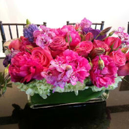 Pink and purple floral arrangement in a low rectangular container