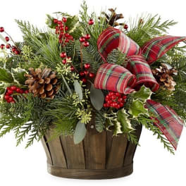 Holiday arrangement in a wooden basket with plaid ribbon and pinecones