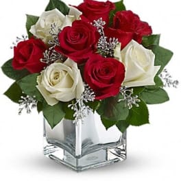 Red and white roses arranged in a clear square vase