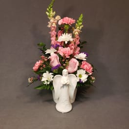 Pink and white flowers arranged in a white angel vase