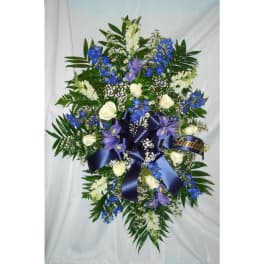Large floral spray with white roses, blue and purple flowers, and a navy ribbon