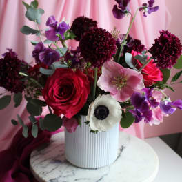 Pink and purple floral arrangement in a white ribbed vase
