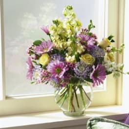 Mixed bouquet of purple and yellow flowers in a clear glass vase