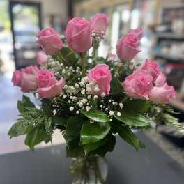 Pink roses arranged in a clear glass vase with baby's breath