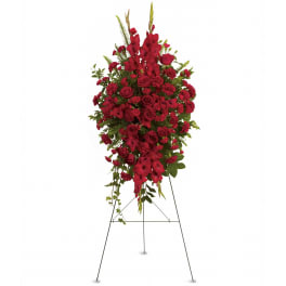 Tall red standing spray with roses, carnations, and gladiolus on a metal easel