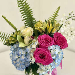 Bouquet of pink roses, blue hydrangeas, and yellow lilies in a glass vase