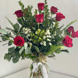 Bouquet of red roses and small white flowers in a clear glass vase