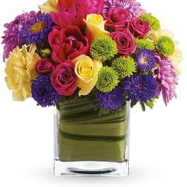 Colorful bouquet of roses, tulips, and chrysanthemums in a clear glass vase