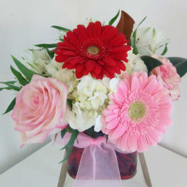 Bouquet of pink and red gerbera daisies with roses in a glass vase