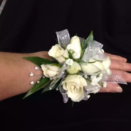 White rose wrist corsage with silver ribbon on a person's wrist