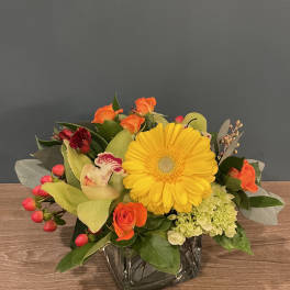 Mixed bouquet with a yellow gerbera daisy in a glass vase