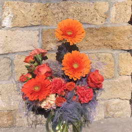 Orange gerberas and red roses in a glass vase