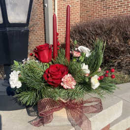 Red roses and carnations arranged with candles in a low holiday centerpiece