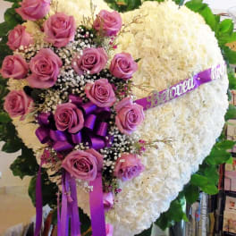 Heart-shaped floral tribute with pink roses and white blooms