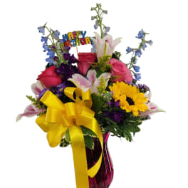 Mixed bouquet with roses, lilies, sunflowers, and a birthday pick in a vase