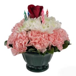 Pink and white floral arrangement in a dark vase with birthday candles