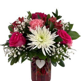 Pink and white flowers arranged in a red glass vase