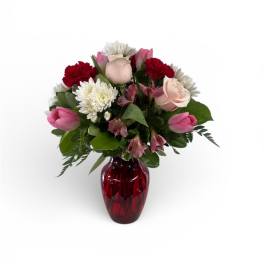 Mixed bouquet in a red glass vase with pink, white, and red blooms
